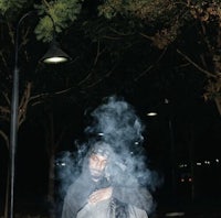 a man smoking a cigarette in a park at night