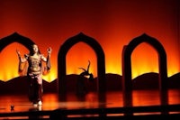 a woman dances on stage in front of an arch