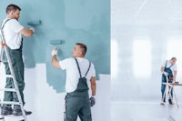 two men painting a wall in a room