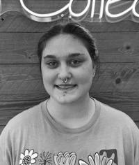 a black and white photo of a girl with piercings in front of a neon sign