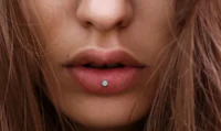 a close up of a woman's mouth with a piercing