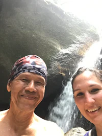a man and woman smiling next to a waterfall
