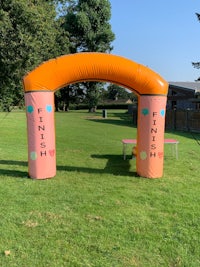 a pink and orange inflatable arch in a grassy field