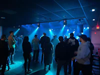 a crowd of people standing in a room with blue lights