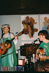 a man and a woman singing and playing an acoustic guitar