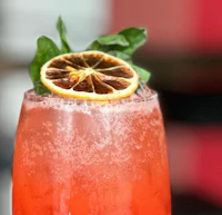a drink with a slice of lemon and a leaf of basil
