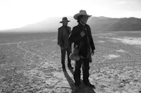 two men in cowboy hats standing in the desert