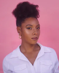 a black woman in a white shirt posing against a pink background