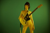 a woman in a yellow outfit holding a guitar
