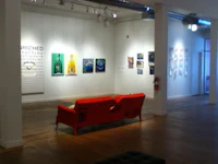 an art gallery with a red couch and paintings on the wall