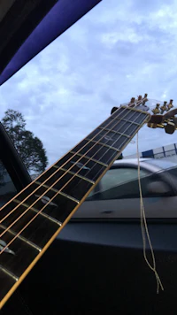 an acoustic guitar hanging from the window of a car