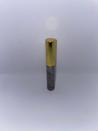 a bottle with a gold lid on a white surface