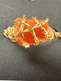 an orange stone with gold wire wrapped around it