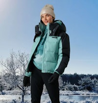 a woman in a blue and black down jacket standing in a snowy area