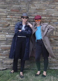 two women standing in front of a brick wall