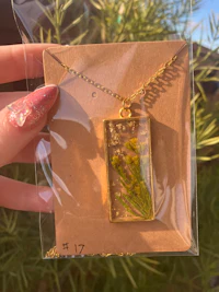 a person holding a necklace with a green leaf in it