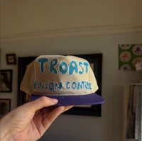 a person holding up a hat that says toast poison control