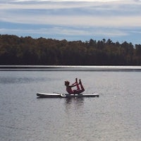 a woman doing yoga on a paddle board in a lake