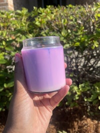 a person holding a purple candle in front of bushes