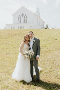 a bride and groom standing in front of a white church