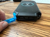 a person using a blue tool to open a power bank
