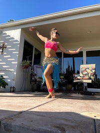 a girl in a pink dress dancing on a patio