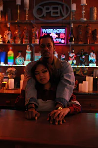 a man and woman posing in front of a bar