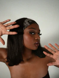 a black woman holding her hands up in front of a white background