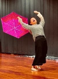 a woman is holding a pink umbrella in the air