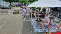 a group of people sitting under a tent in a parking lot