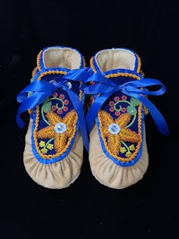 a pair of blue and yellow moccasins with a blue ribbon