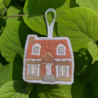 a gingerbread house ornament hanging on a leaf