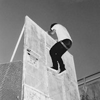 black and white photo of a skateboarder on top of a wall
