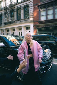 a woman in a pink jacket walking down the street