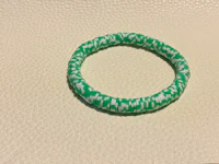 a green and white braided bracelet on a table