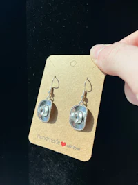a person holding a pair of earrings on a card