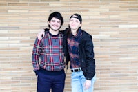 two people standing in front of a brick wall