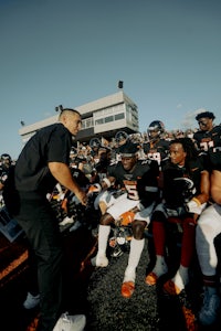 a group of football players sitting on the sidelines