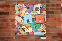 a piece of art hanging on a brick wall