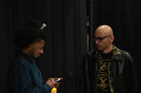 two men looking at a cell phone in a dark room