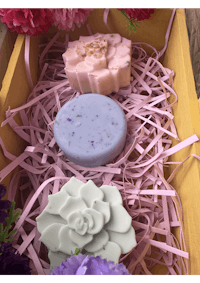 three soaps in a wooden box filled with flowers