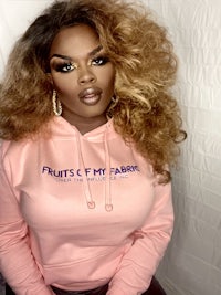 a woman wearing a pink hoodie with the words fruits & fancies