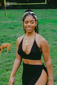a woman in a black bikini standing in a grassy area