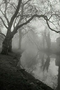 a black and white photo of a foggy river