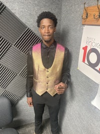 a man in a vest standing in front of a microphone