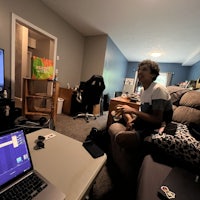 a boy sits on a couch in a living room with a laptop