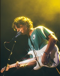 a man playing a guitar in front of a microphone