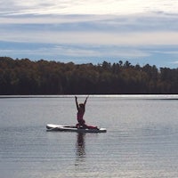 a woman practicing yoga on a paddle board in a lake