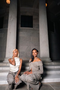 two women sitting on the steps of a building