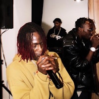 two men with dreadlocks standing in front of a microphone